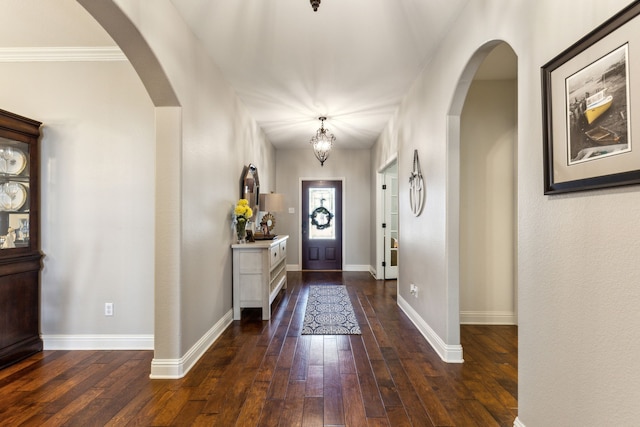 entrance foyer with wood-type flooring, arched walkways, baseboards, and a chandelier