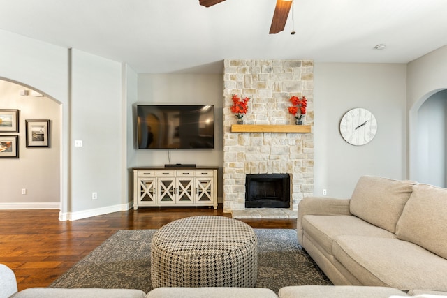1250 Amistad Dr, Prosper, TX 75078 - living room featuring arched walkways, wood finished floors, a ceiling fan, baseboards, and a stone fireplace