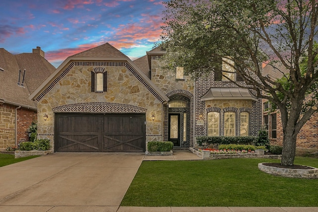 french country inspired facade with stone siding, a front yard, an attached garage, and driveway
