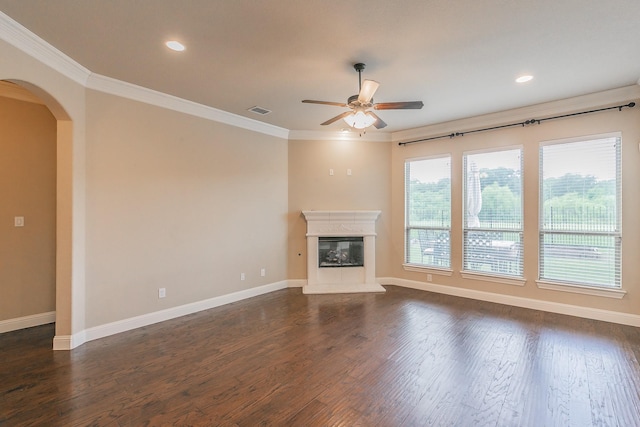 unfurnished living room featuring ceiling fan, arched walkways, ornamental molding, baseboards, and recessed lighting