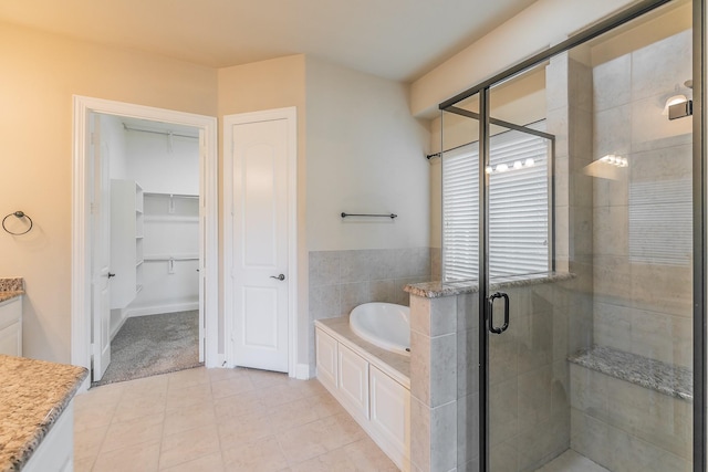 full bathroom with a stall shower, vanity, a bath, tile patterned floors, and a walk in closet