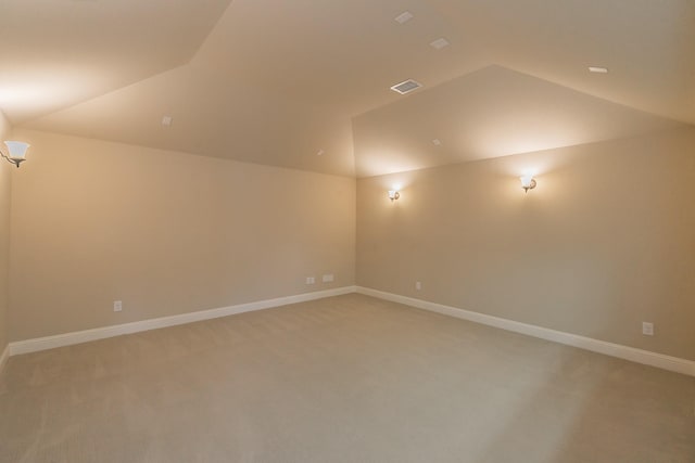 empty room with vaulted ceiling, light colored carpet, and baseboards