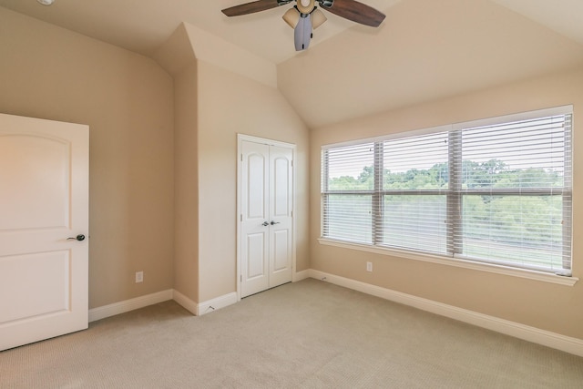 unfurnished bedroom with light colored carpet, vaulted ceiling, baseboards, a closet, and ceiling fan