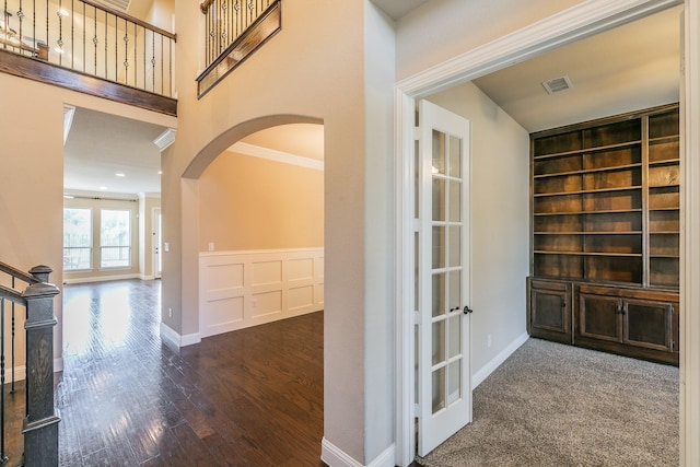 hallway featuring arched walkways, wood finished floors, built in features, and baseboards