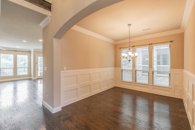 unfurnished dining area featuring crown molding, wainscoting, dark wood finished floors, arched walkways, and a decorative wall