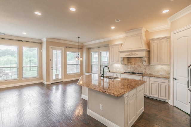 kitchen featuring custom exhaust hood, a sink, stainless steel gas cooktop, light stone countertops, and tasteful backsplash