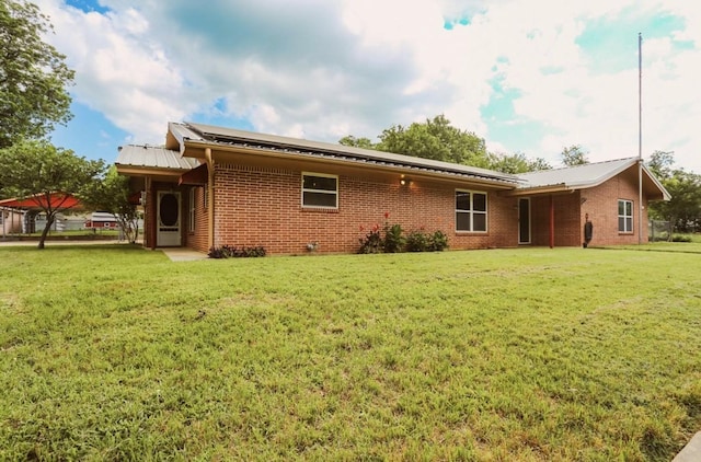 405 W Neely Ave, Comanche, TX 76442 - back of house with brick siding, a yard, and metal roof