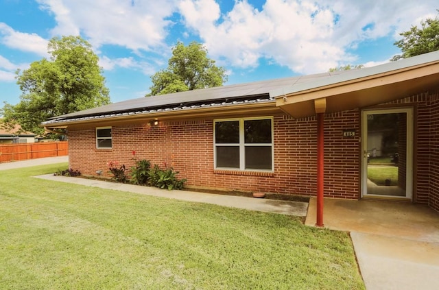 405 W Neely Ave, Comanche, TX 76442 - view of property exterior featuring brick siding, roof mounted solar panels, and a patio area