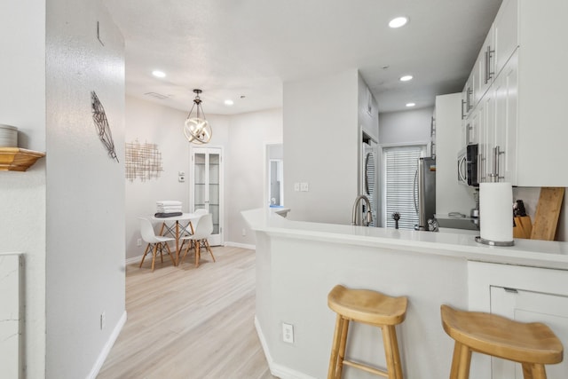 4800 W Lovers Ln Unit 113, Dallas, TX 75209 - kitchen with stainless steel appliances, white cabinets, light wood-type flooring, a kitchen bar, and recessed lighting