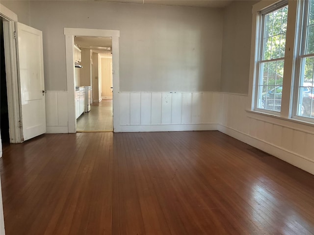 118 S 31st St, Corsicana, TX 75110 - unfurnished room featuring wainscoting, dark wood-style flooring, and healthy amount of natural light