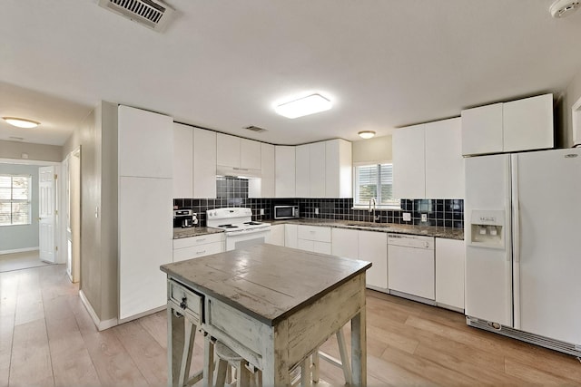 1508 E Dellis St, Kaufman, TX 75142 - kitchen featuring white appliances, light wood-style floors, backsplash, a sink, and white cabinetry