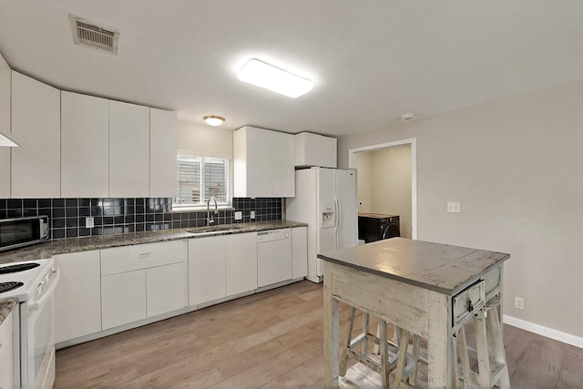 1508 E Dellis St, Kaufman, TX 75142 - kitchen with white appliances, a sink, backsplash, light wood finished floors, and white cabinetry