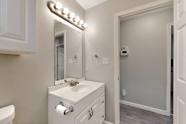 1508 E Dellis St, Kaufman, TX 75142 - bathroom featuring wood finished floors, vanity, toilet, and baseboards