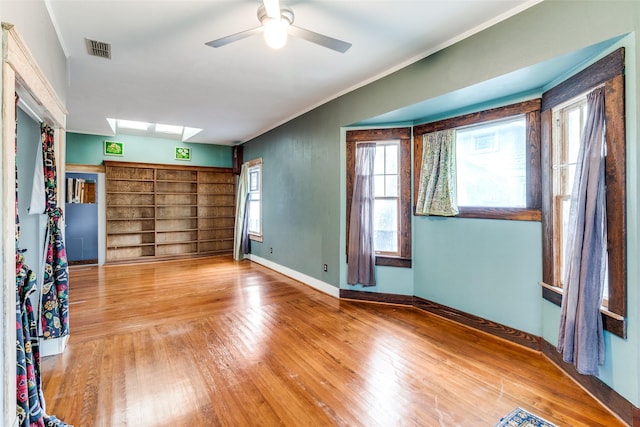 5020 Junius St, Dallas, TX 75214 - empty room featuring a skylight, wood finished floors, crown molding, ceiling fan, and built in shelves