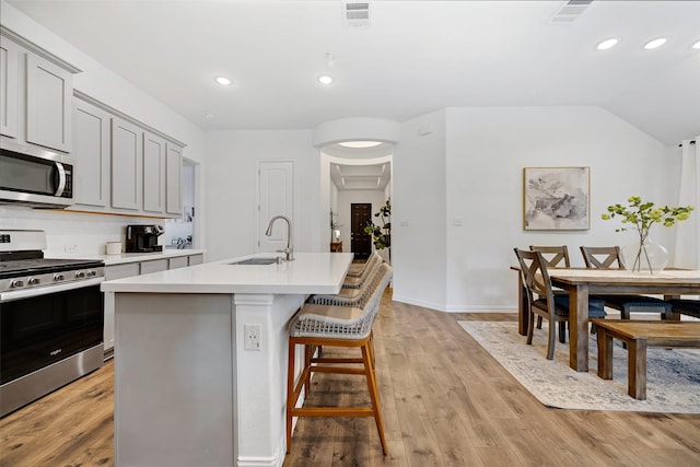 2434 Solomons Pl, Wylie, TX 75098 - kitchen with appliances with stainless steel finishes, a sink, a kitchen island with sink, light countertops, and light wood-type flooring