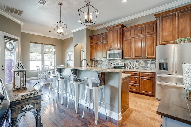 9001 Magnolia Vale Dr, Granbury, TX 76049 - kitchen featuring appliances with stainless steel finishes, a chandelier, light wood-style flooring, a breakfast bar area, and recessed lighting