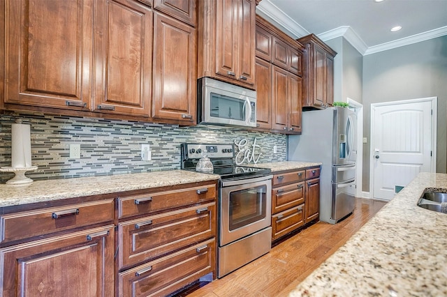 9001 Magnolia Vale Dr, Granbury, TX 76049 - kitchen with stainless steel appliances, crown molding, light wood-type flooring, decorative backsplash, and light stone countertops