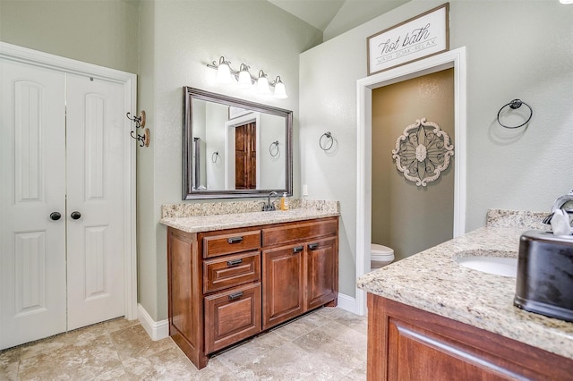 9001 Magnolia Vale Dr, Granbury, TX 76049 - bathroom with two vanities, baseboards, toilet, and vaulted ceiling