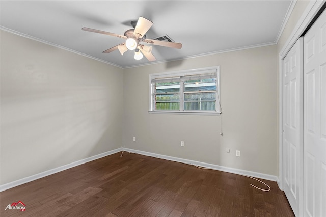unfurnished bedroom featuring dark wood-style floors, ornamental molding, baseboards, a closet, and ceiling fan
