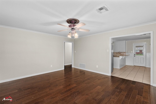 empty room featuring a ceiling fan, ornamental molding, wood finished floors, and baseboards