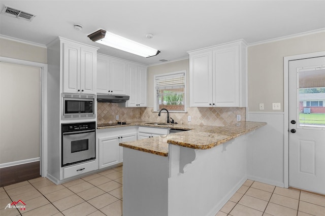 kitchen featuring stainless steel appliances, a sink, ornamental molding, white cabinets, and light tile patterned floors