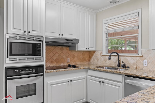 kitchen featuring stainless steel appliances, a sink, under cabinet range hood, white cabinetry, and ornamental molding