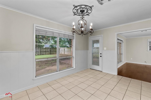 unfurnished dining area with ornamental molding, a wainscoted wall, and a chandelier