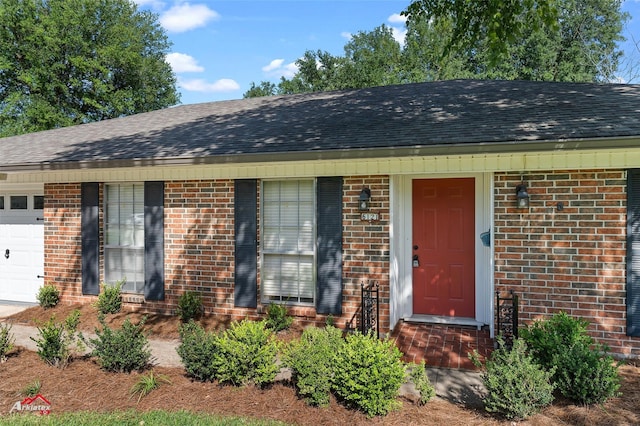 ranch-style home with an attached garage, brick siding, and roof with shingles