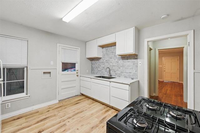 4808 Birchman Ave, Fort Worth, TX 76107 - kitchen featuring black range with gas stovetop, a sink, light wood-type flooring, light countertops, and a textured ceiling
