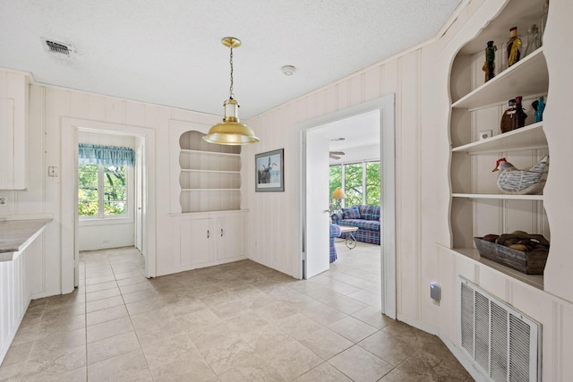 219 Ray Rd, Pottsboro, TX 75076 - unfurnished dining area with built in features, healthy amount of natural light, a textured ceiling, light tile patterned floors, and wooden walls
