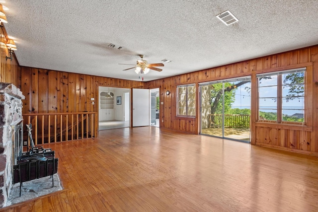 219 Ray Rd, Pottsboro, TX 75076 - unfurnished living room with wood finished floors, a ceiling fan, wooden walls, and a textured ceiling