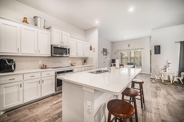 6505 Boot Jack Dr, Burleson, TX 76058 - kitchen with stainless steel appliances, a sink, light wood-style floors, a kitchen island with sink, and backsplash