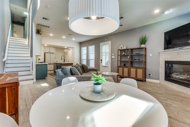 5006 Mission Ave, Dallas, TX 75206 - dining space with light wood-style flooring, a tile fireplace, stairway, baseboards, and recessed lighting