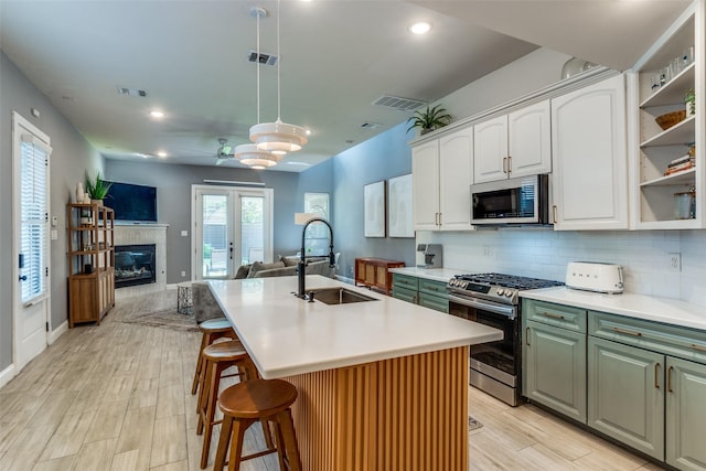 5006 Mission Ave, Dallas, TX 75206 - kitchen featuring stainless steel appliances, a sink, open floor plan, white cabinets, and light countertops