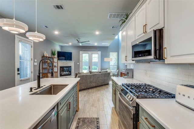 5006 Mission Ave, Dallas, TX 75206 - kitchen with stainless steel appliances, a sink, light countertops, a tile fireplace, and decorative backsplash
