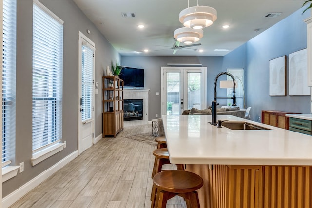 5006 Mission Ave, Dallas, TX 75206 - kitchen featuring a sink, a ceiling fan, open floor plan, light wood-style floors, and a tiled fireplace