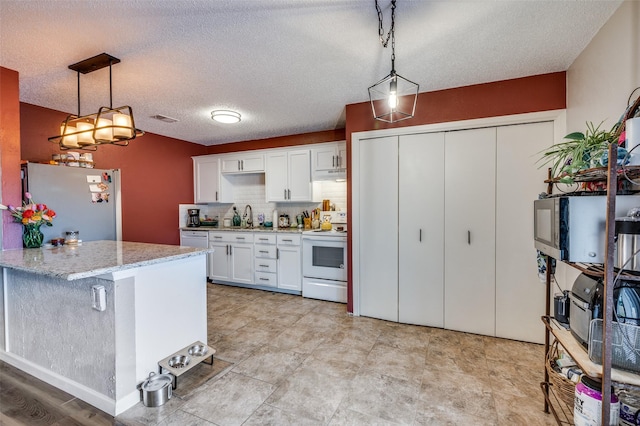 kitchen with electric range, freestanding refrigerator, a sink, white cabinets, and under cabinet range hood