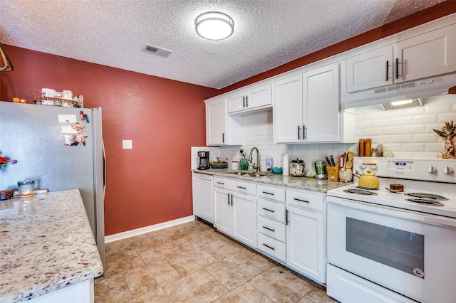 kitchen with white appliances, under cabinet range hood, a sink, tasteful backsplash, and a textured ceiling