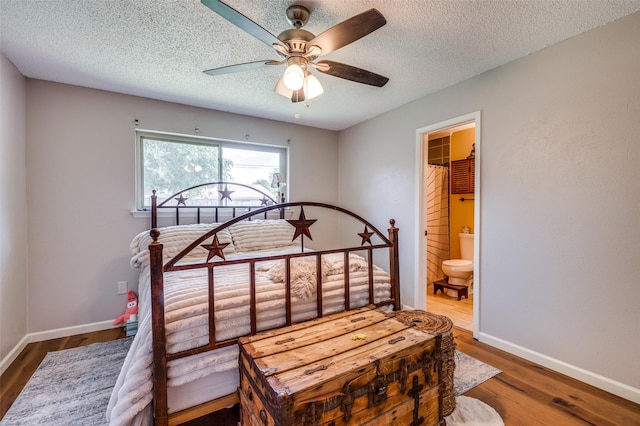 bedroom featuring wood finished floors, baseboards, a textured ceiling, and ensuite bath