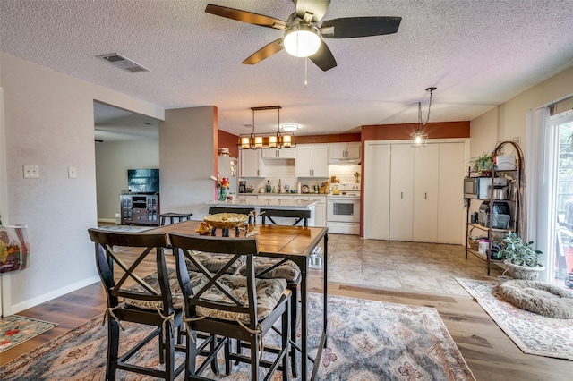 dining space featuring ceiling fan, wood finished floors, a textured ceiling, and baseboards