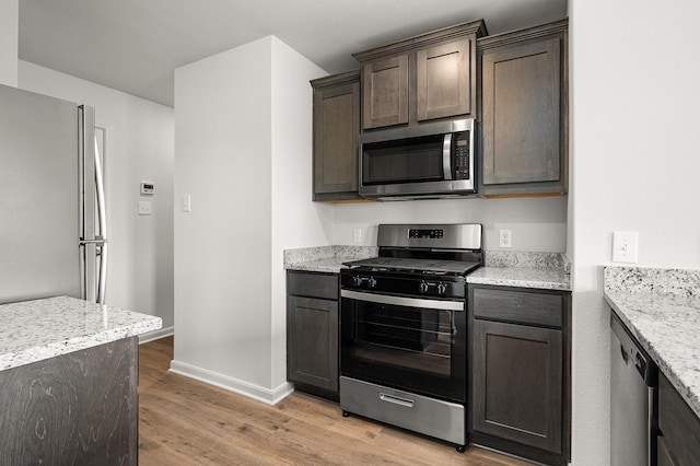 432 Gib Woodall Dr, Venus, TX 76084 - kitchen featuring stainless steel appliances, light wood-style flooring, baseboards, dark brown cabinetry, and light stone countertops