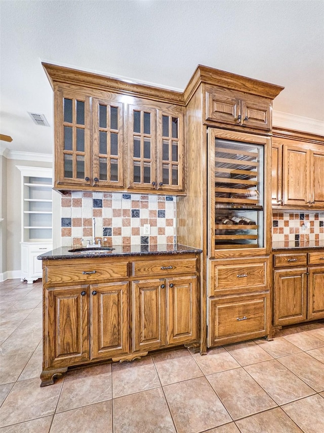 2215 Firestone Cir, Tyler, TX 75703 - kitchen featuring a sink, decorative backsplash, crown molding, brown cabinets, and glass insert cabinets