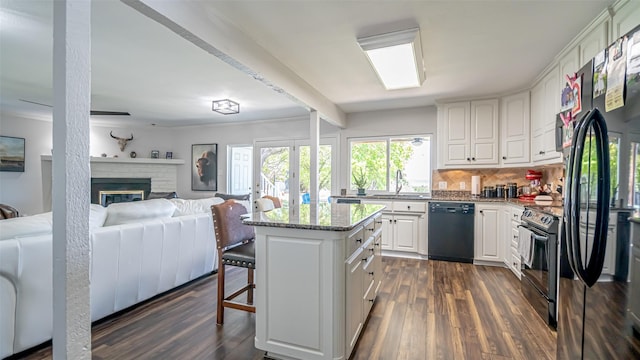 4536 Overlook Ct, Granbury, TX 76049 - kitchen featuring black appliances, a sink, open floor plan, white cabinets, and a breakfast bar area