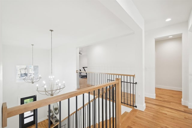 corridor featuring an upstairs landing, a chandelier, baseboards, wood finished floors, and recessed lighting