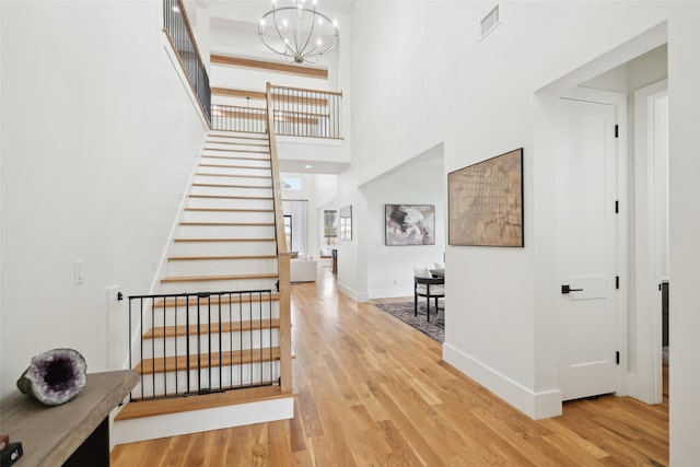 foyer entrance with stairs, wood finished floors, a chandelier, and a high ceiling