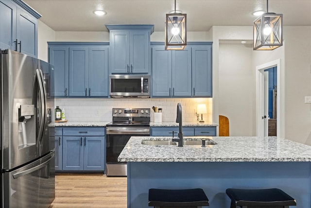2610 Austin Dr, Granbury, TX 76048 - kitchen featuring stainless steel appliances, blue cabinetry, a sink, light wood-style flooring, and a kitchen bar