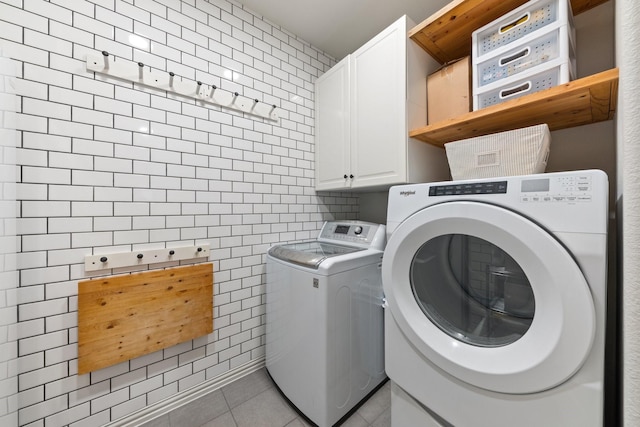 14322 Summerwoods Ln, Frisco, TX 75035 - laundry room with washing machine and clothes dryer, light tile patterned flooring, tile walls, and cabinet space