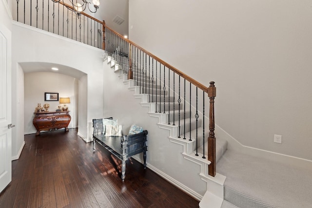 14322 Summerwoods Ln, Frisco, TX 75035 - stairs with arched walkways, wood-type flooring, a high ceiling, a chandelier, and baseboards