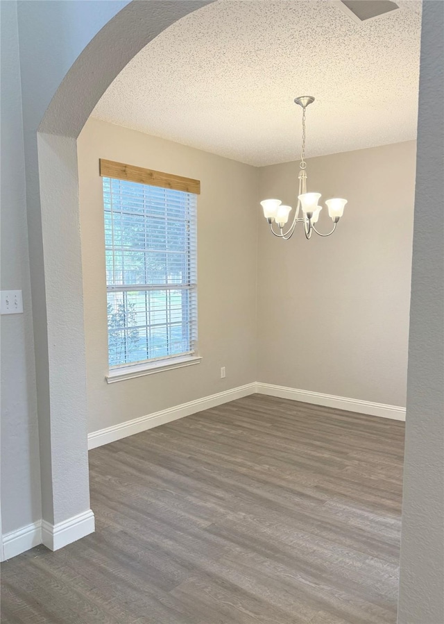 207 Trailwood Dr, Allen, TX 75002 - spare room with arched walkways, a chandelier, wood finished floors, baseboards, and a textured ceiling