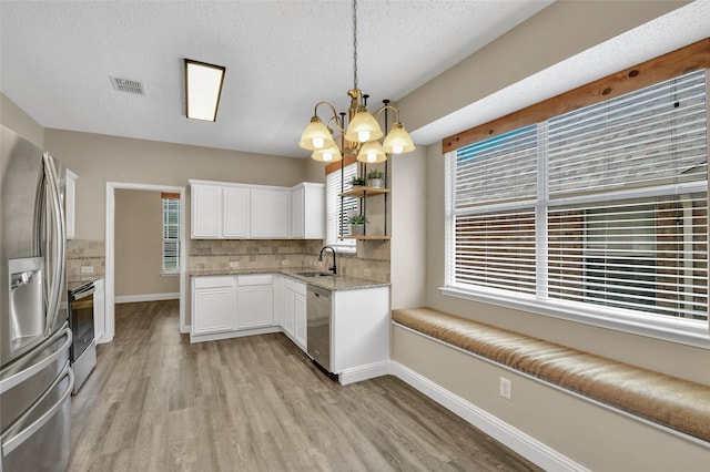 207 Trailwood Dr, Allen, TX 75002 - kitchen with stainless steel appliances, a chandelier, light wood finished floors, white cabinetry, and open shelves